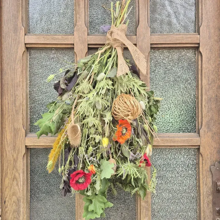 Festoen van droogbloemen aan een oude deur