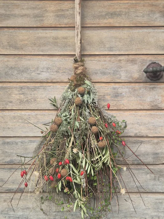 Een tafelschikking met zinnia's en sierappeltjes, een bezemsteel met gedroogde bloemen en rozenbottels, en een stuk voor Allerheiligen met rozen en asters