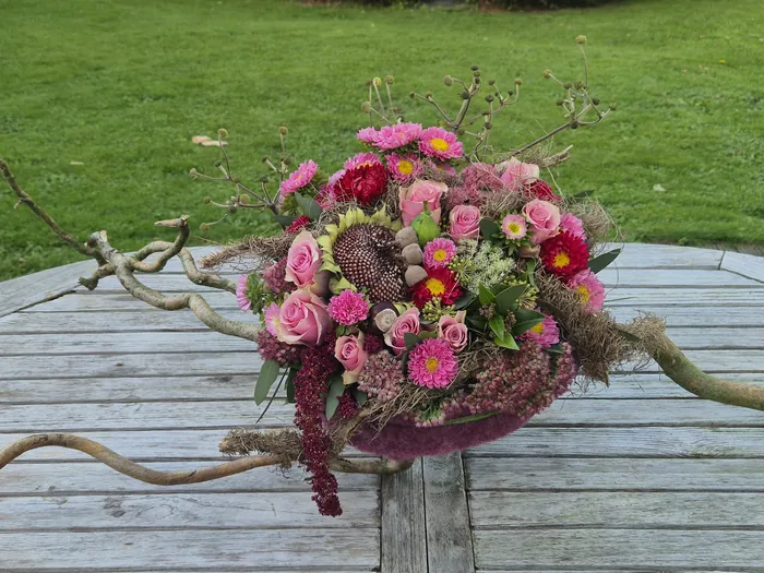 Een tafelschikking met zinnia's en sierappeltjes, een bezemsteel met gedroogde bloemen en rozenbottels, en een stuk voor Allerheiligen met rozen en asters