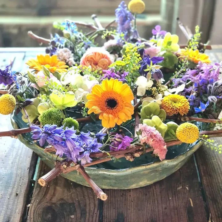 Bloemschikking op een zelfgemaakt raster van takken in een schaal